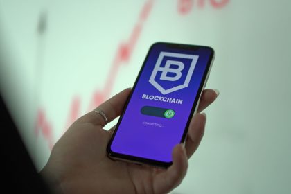 Mão segurando um smartphone com uma carteira digital de criptomoedas exibida na tela.