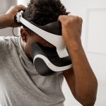 Homem ajusta um headset de realidade virtual em um ambiente interno bem iluminado.