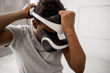 Homem ajusta um headset de realidade virtual em um ambiente interno bem iluminado.