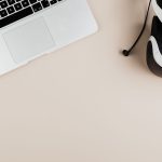 Laptop e headset de realidade virtual dispostos sobre uma superfície clara.