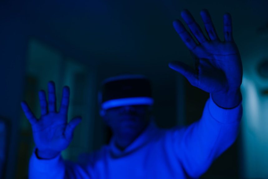 Homem usando headset de realidade virtual e interagindo com as mãos em um ambiente iluminado por luz azul.