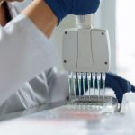 Cientista usando uma pipeta multicanal para manusear líquidos em um laboratório.