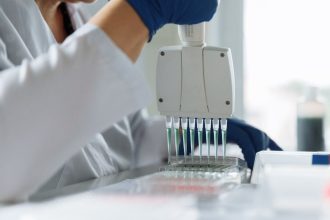 Cientista usando uma pipeta multicanal para manusear líquidos em um laboratório.