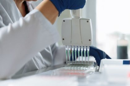 Cientista usando uma pipeta multicanal para manusear líquidos em um laboratório.